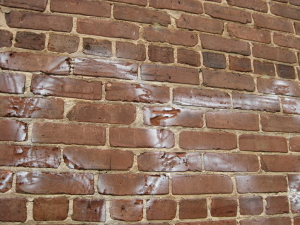 Example of irreversible damage to brick by high-pressure wash and very little graffiti removed.